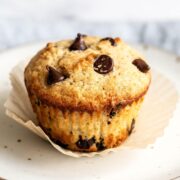 Chocolate chip muffin on a plate with the paper liner removed