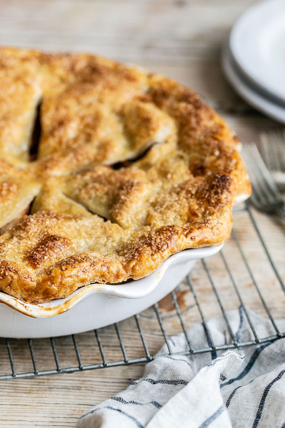 Double crust apple pie on a cooling rack on a wooden table