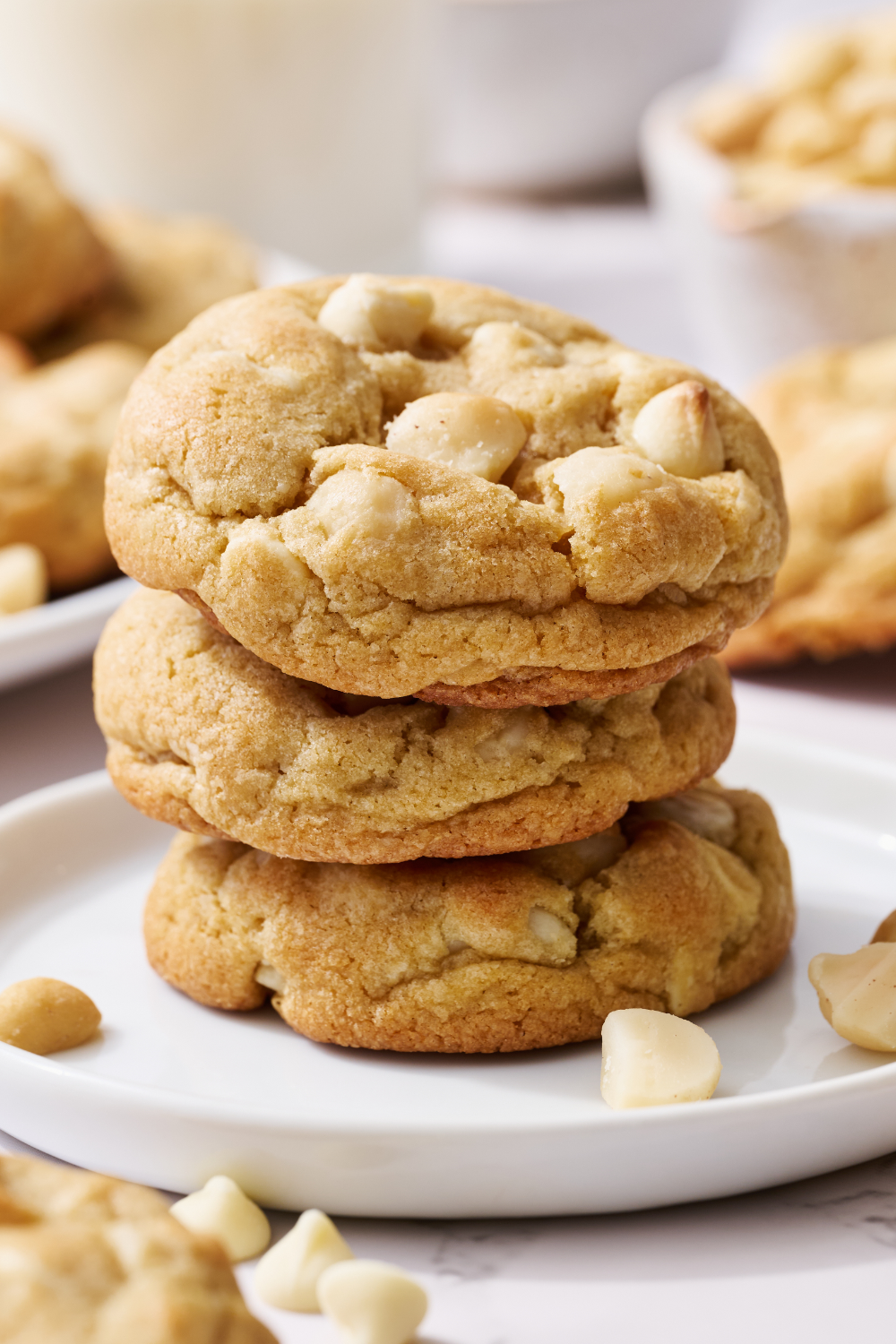 a stack of three White Chocolate Macadamia Nut Cookies on a white plate.