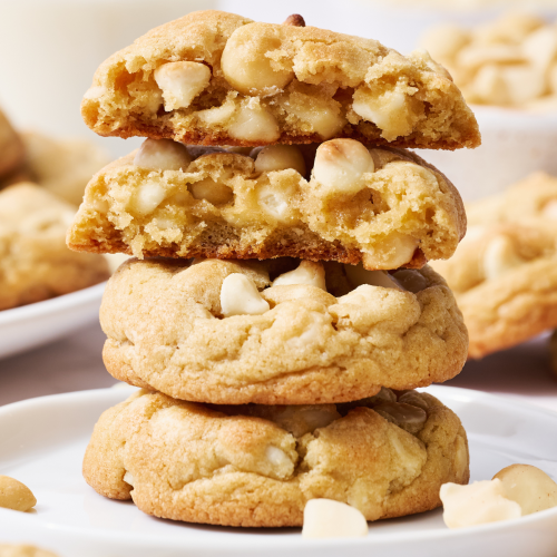 a stack of White Chocolate Macadamia Nut Cookies on a plate with chips and nuts around.