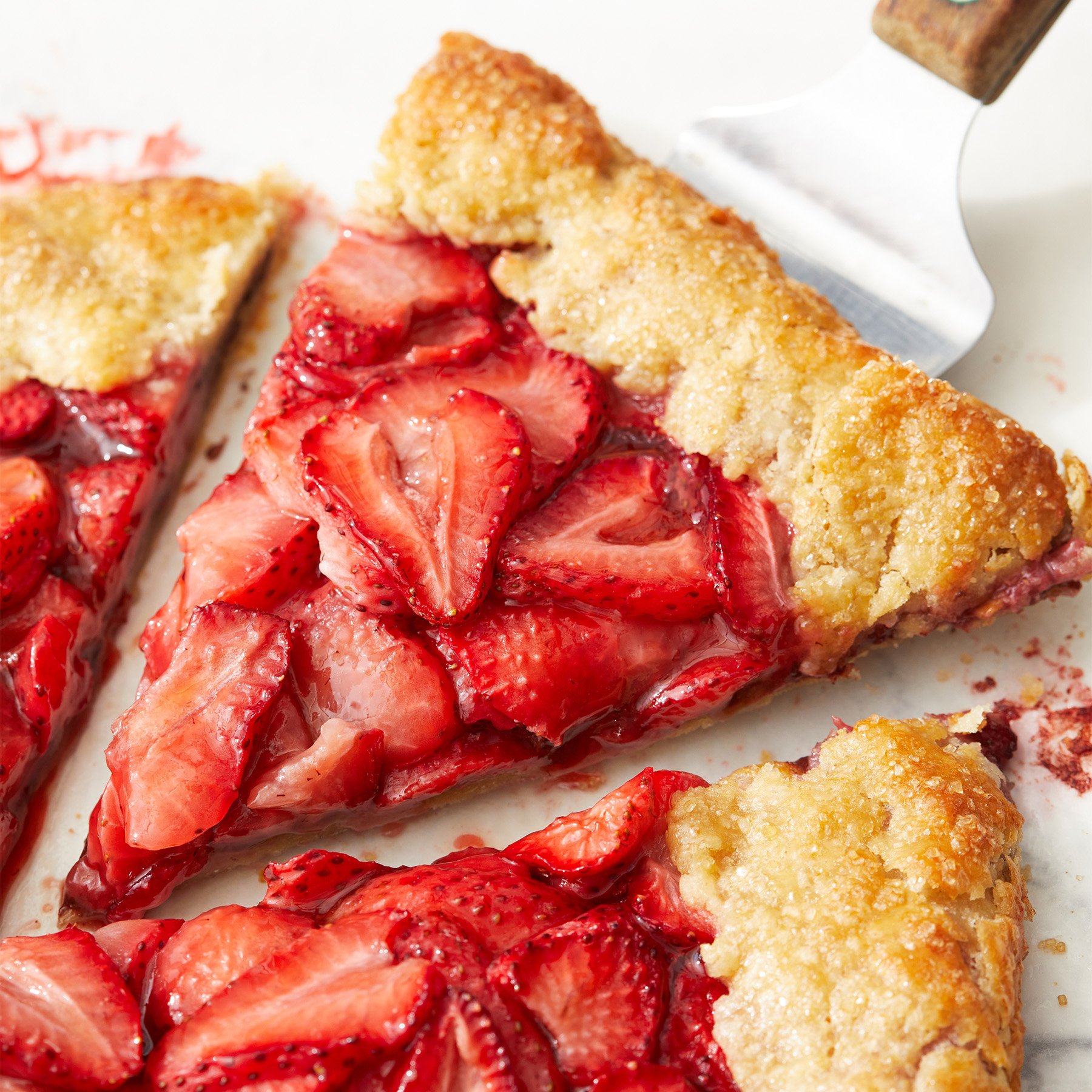 slice of homemade strawberry galette being pulled out of galette