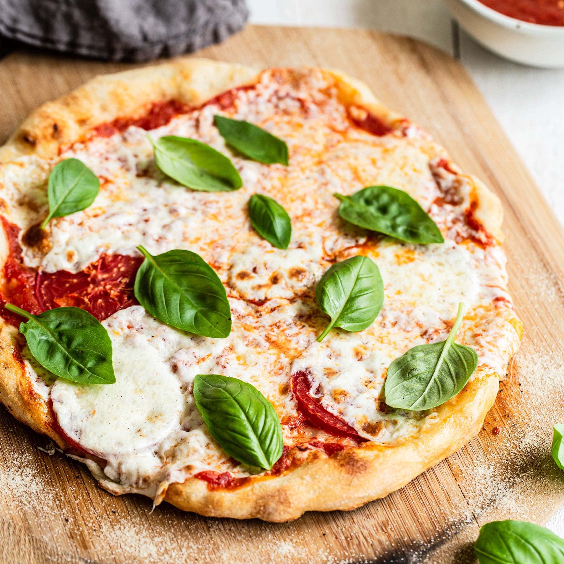 homemade pizza dough with easy pizza sauce, mozzarella, tomatoes and fresh basil on top