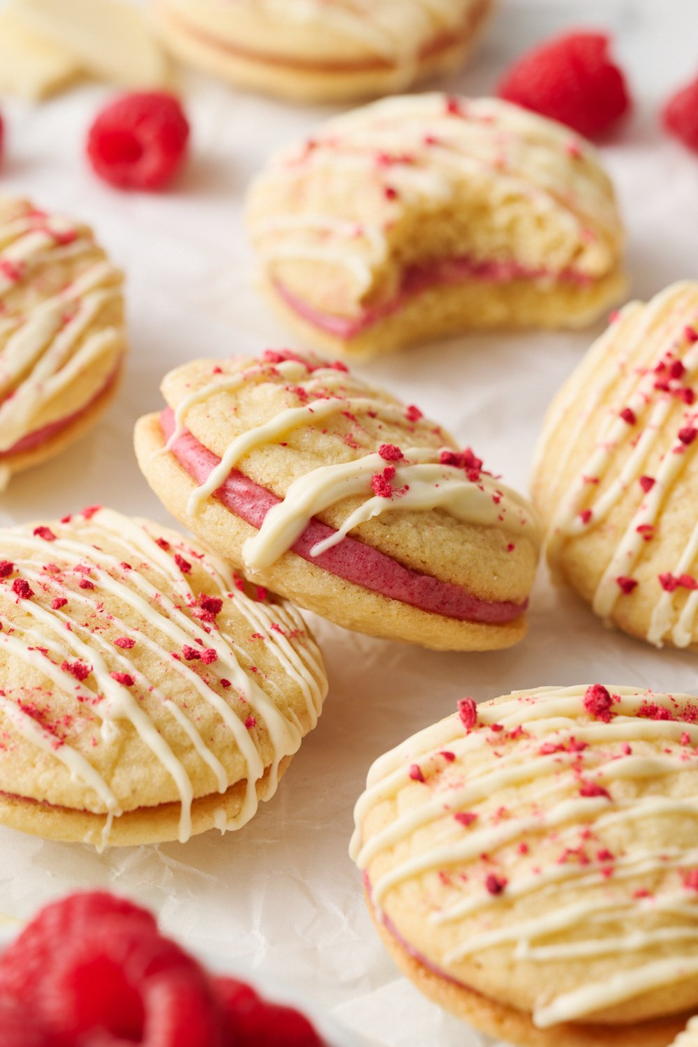 several Raspberry Cream Sandwich Cookies decorated with white chocolate and crushed freeze-dried raspberries.