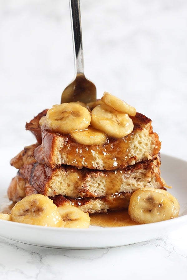 Bananas Foster French Toast stack with bananas and a fork, ready to enjoy
