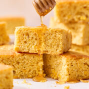 easy cornbread recipe on parchment paper with honey being drizzled on top