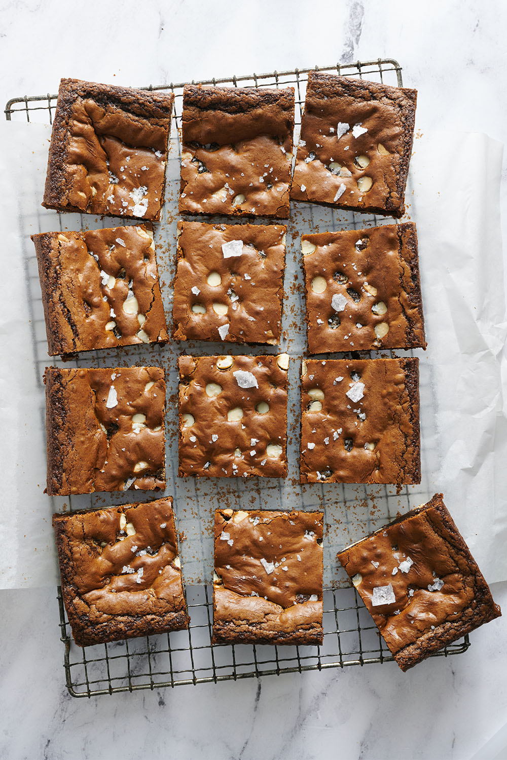 sliced Gingerbread White Chocolate Blondies on a cooling rack on top of a marble surface.