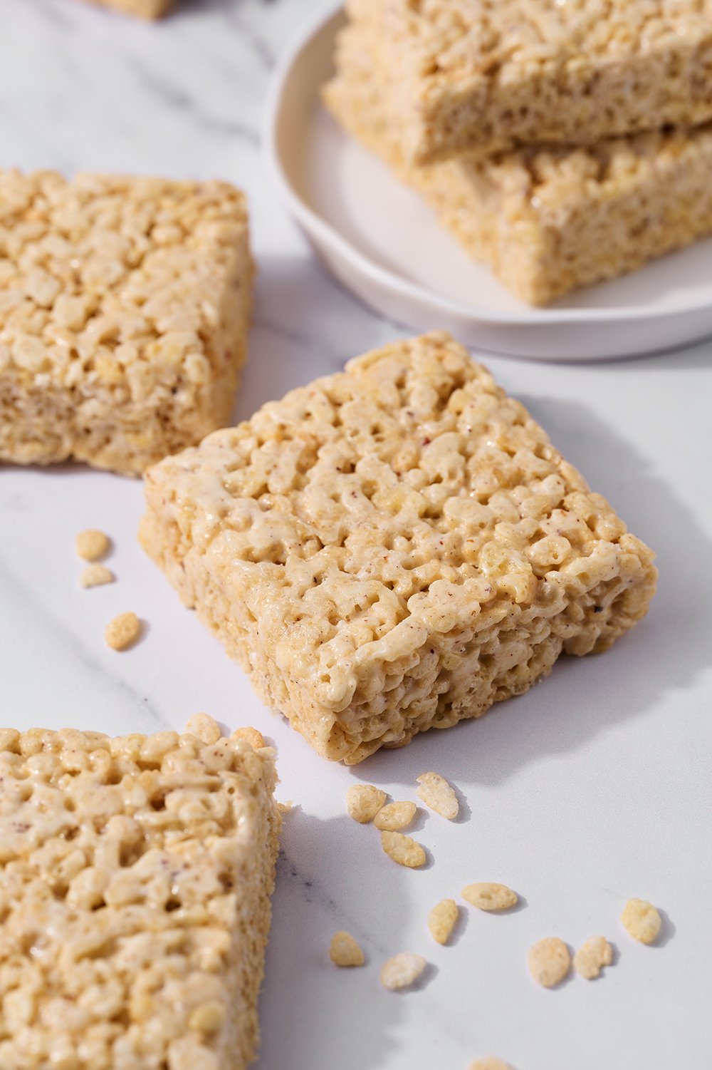 slices of Brown Butter Rice Crispy Treats with some Rice Crispy cereal scattered between