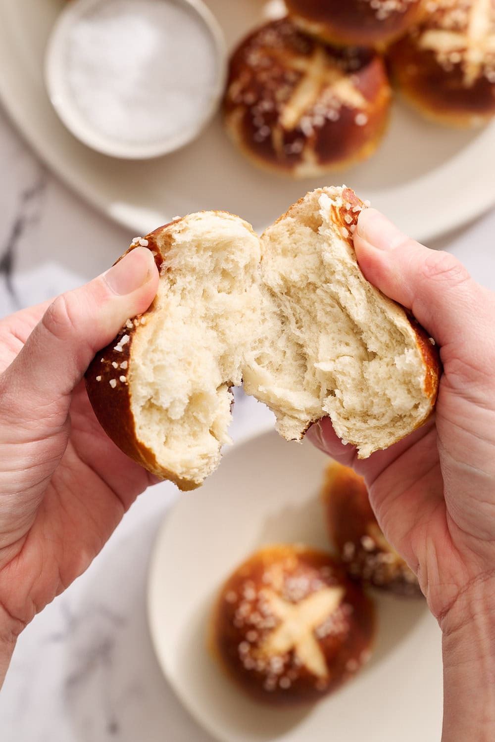 tearing open a pretzel bun to show the soft and chewy interior