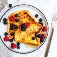 French toast with berries and maple syrup on a plate