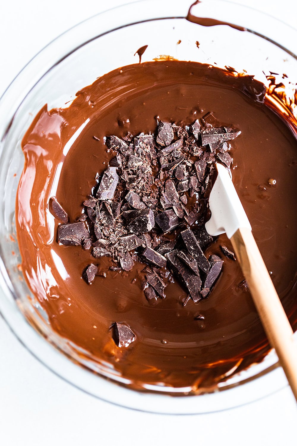 tempered chocolate with more chunks of chocolate on top in a glass bowl