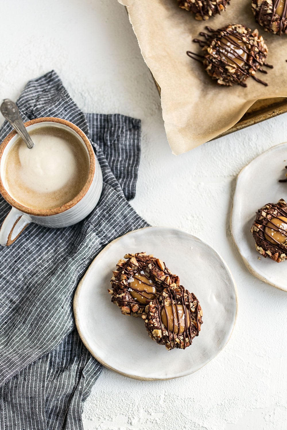 This Turtle Thumbprint Cookie recipe features a cocoa cookie rolled in pecans, filled with a salted caramel thumbprint, and drizzled with chocolate. A perfect Christmas cookie recipe! 
