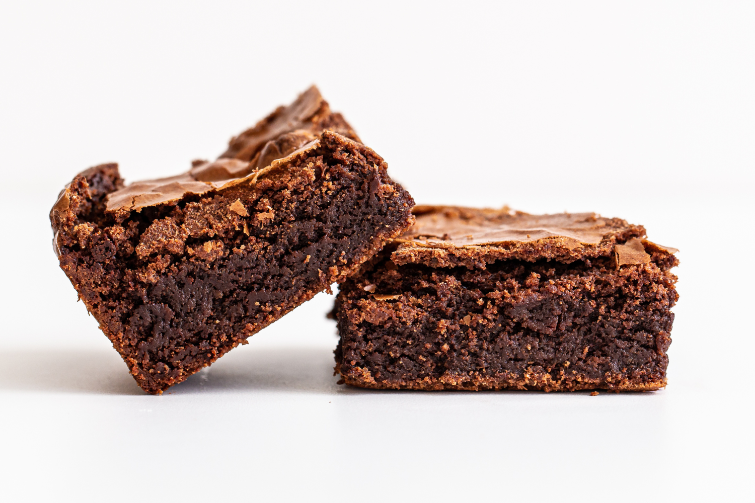two fudgy brownies stacked on top of each other, showing the gorgeous shiny crust and the rich, fudgy center