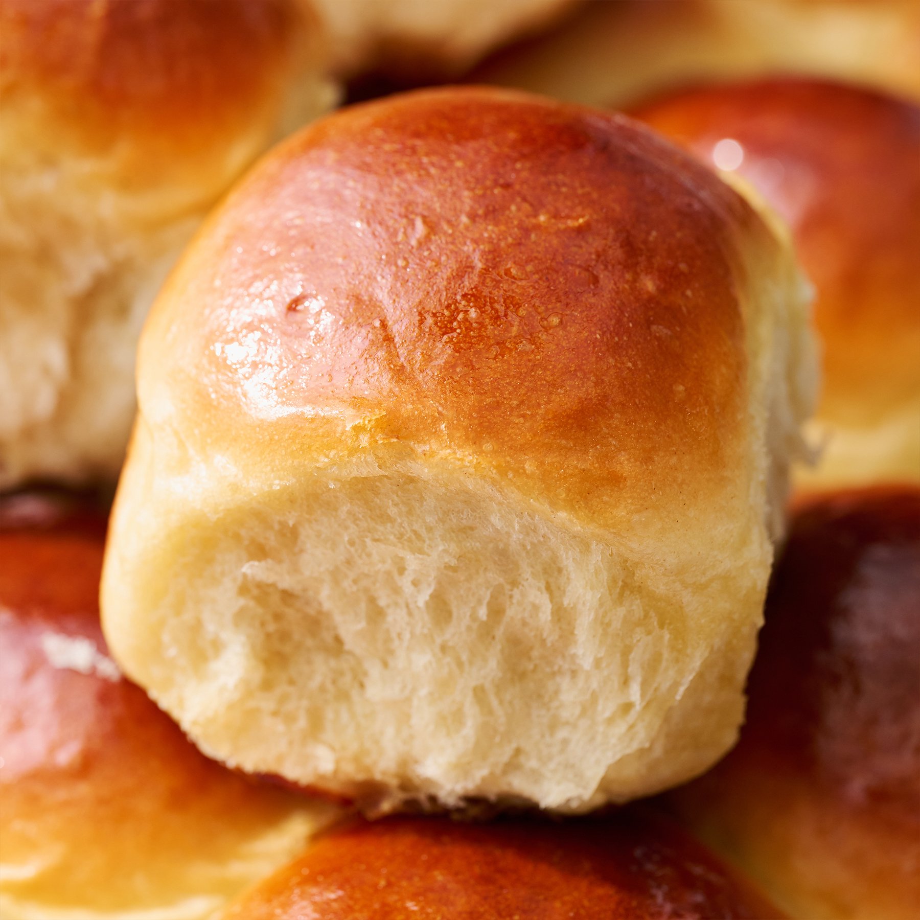 a single hawaiian bread roll on in a baking pan on top of other bread rolls