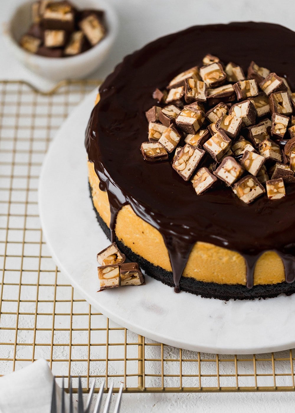 Snickers Cheesecake with Oreo crust, cheesecake filling loaded with Snickers, thick chocolate ganache, and more Snickers on top! Ultimate decadence.