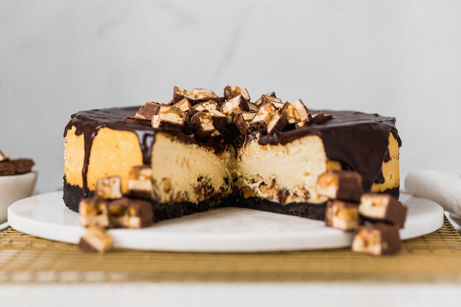 Snickers Cheesecake recipe with Oreo crust, cheesecake filling loaded with Snickers, thick chocolate ganache, and more Snickers on top! Ultimate decadence.