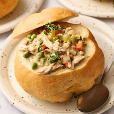 homemade bread bowl filled with soup on a plate with a spoon