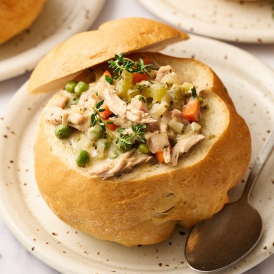 homemade bread bowl recipe filled with soup on a plate with a spoon