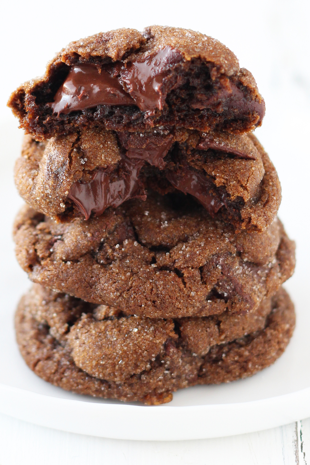 a stack of Chewy Chocolate Gingerbread Cookies with the top cookie broken in half to show the gooey interior.