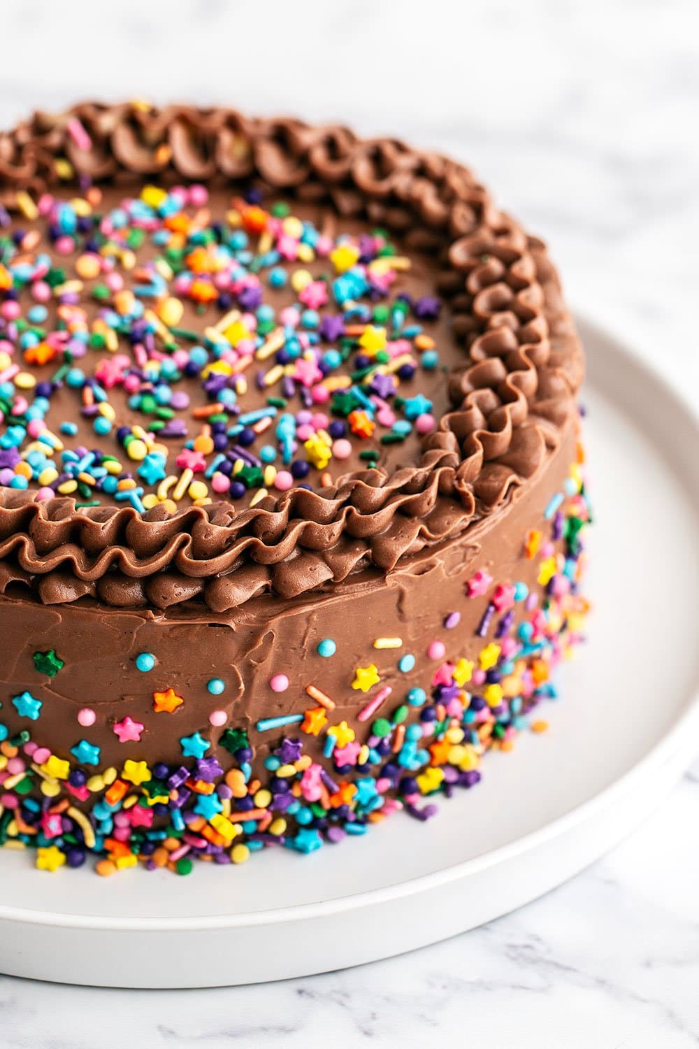 Birthday cake on platter with sprinkles on top