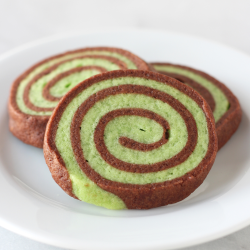 three mint chocolate pinwheel cookies on a plate, ready to serve.