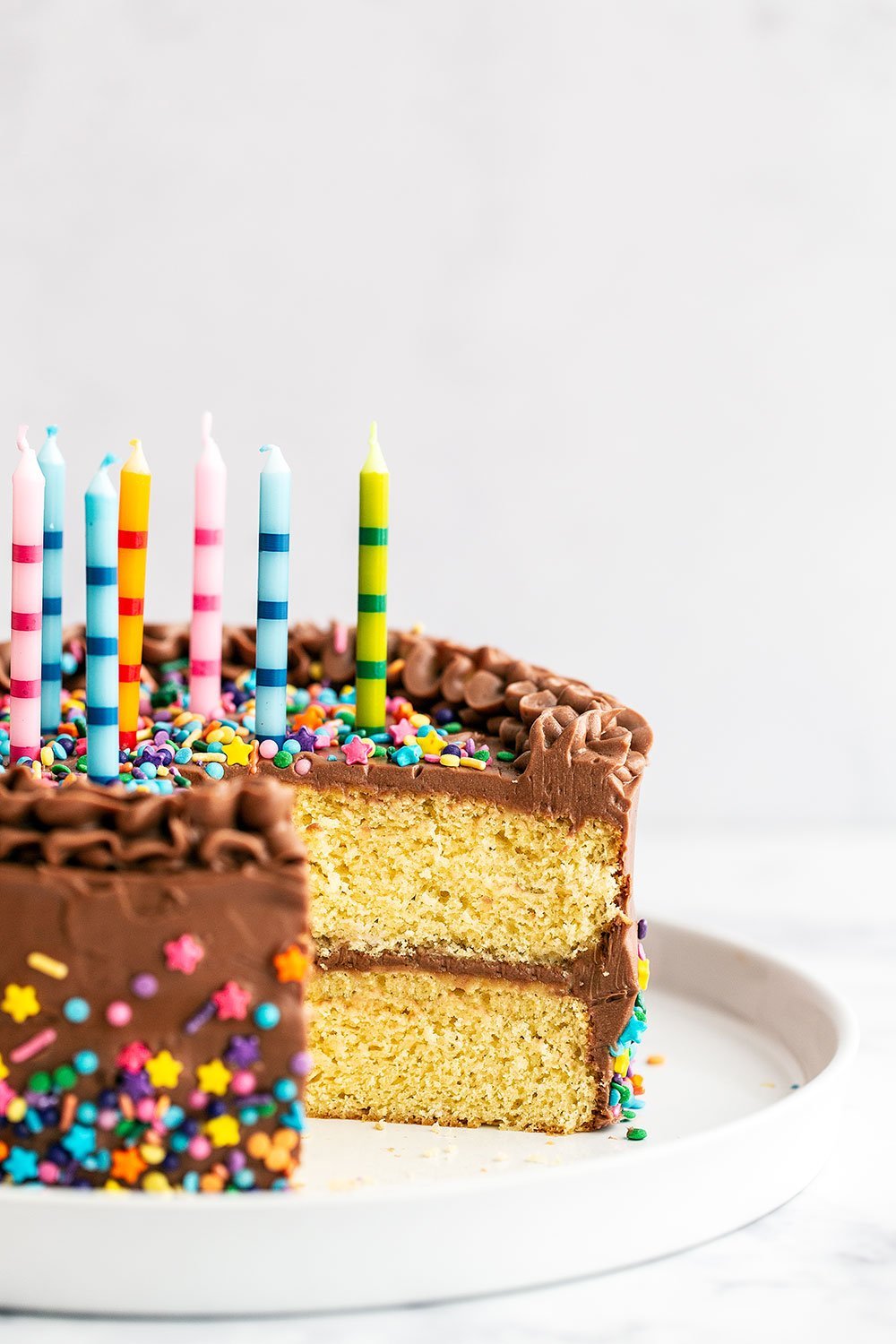 Birthday cake on platter with slice taken out