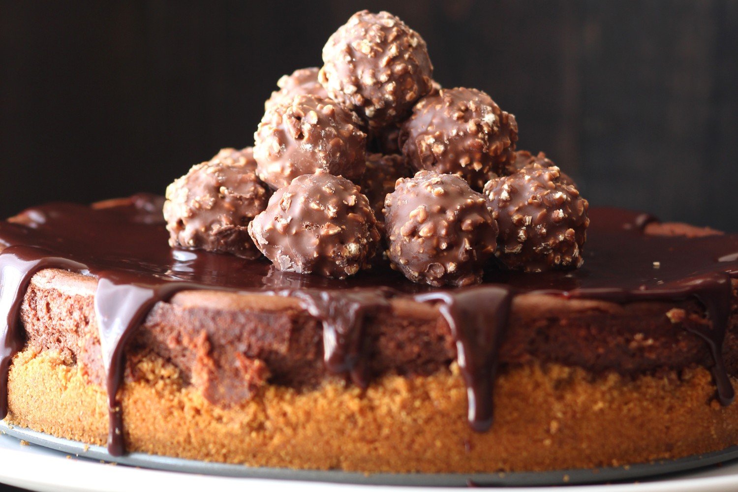 whole unsliced nutella cheesecake on a white cake stand.