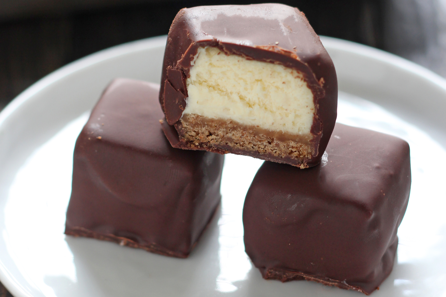 a stack of cheesecake bites covered in chocoalte.