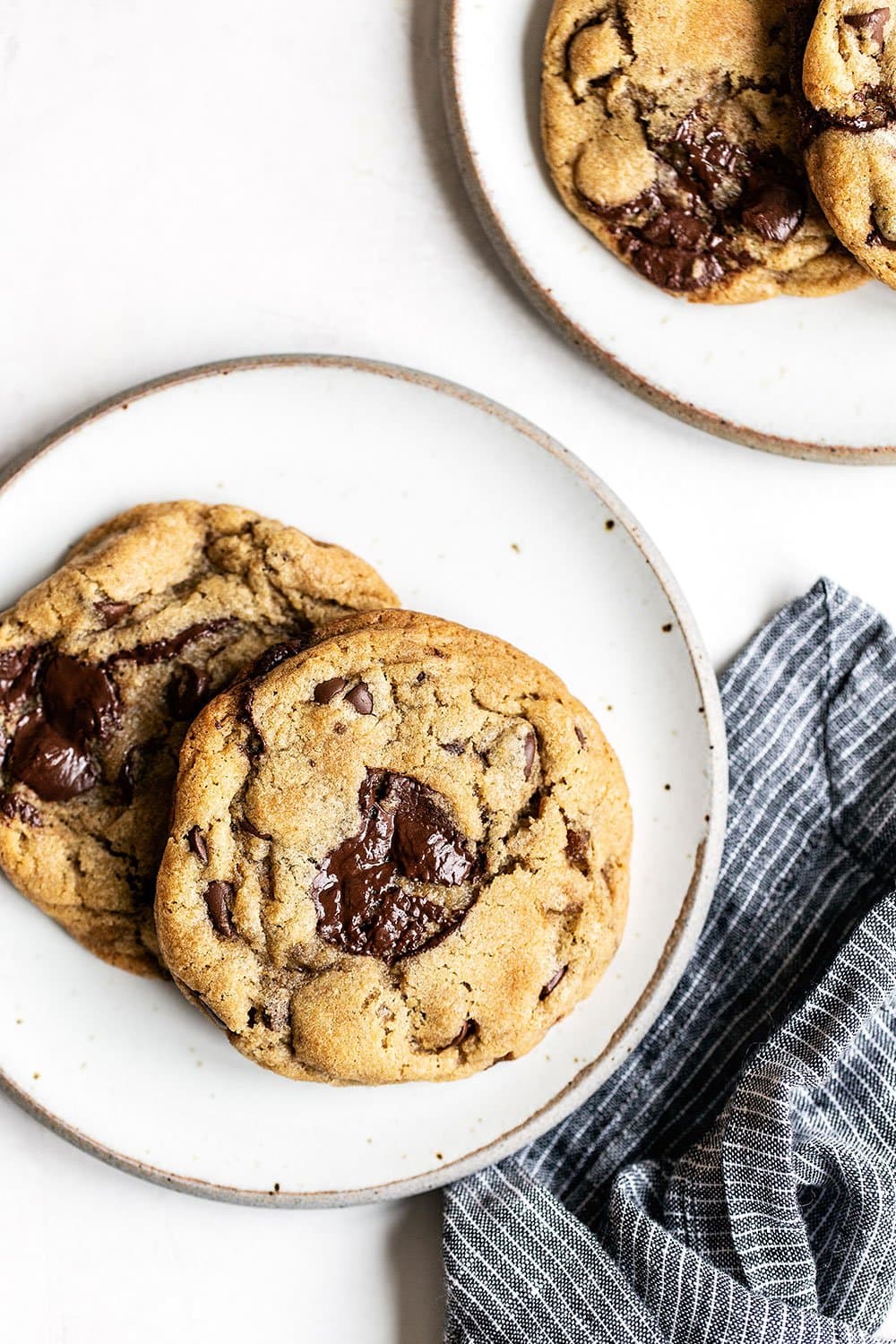 Two chocolate chip cookies on a plate with a cloth napkin