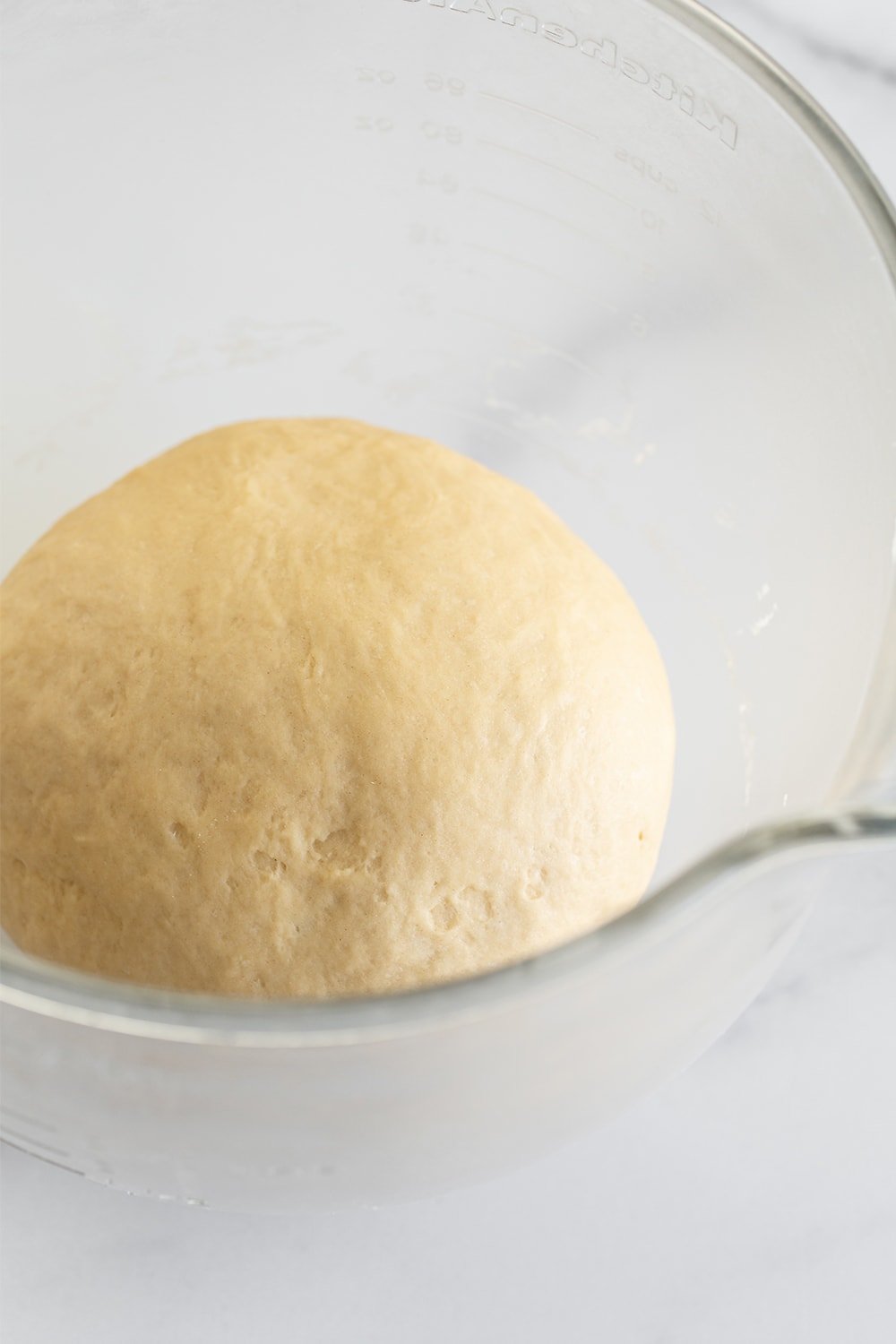 rising dough in a glass bowl