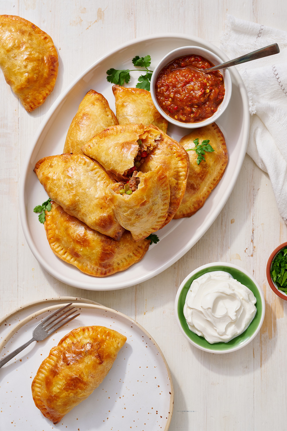 beef empanada on a plate with some salsa and sour cream for dipping