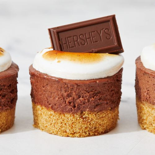 no bake smores mini cheesecake with graham cracker crust, chocolate cheesecake layer, meringue topping, and a hersheys chocolate bar square on top