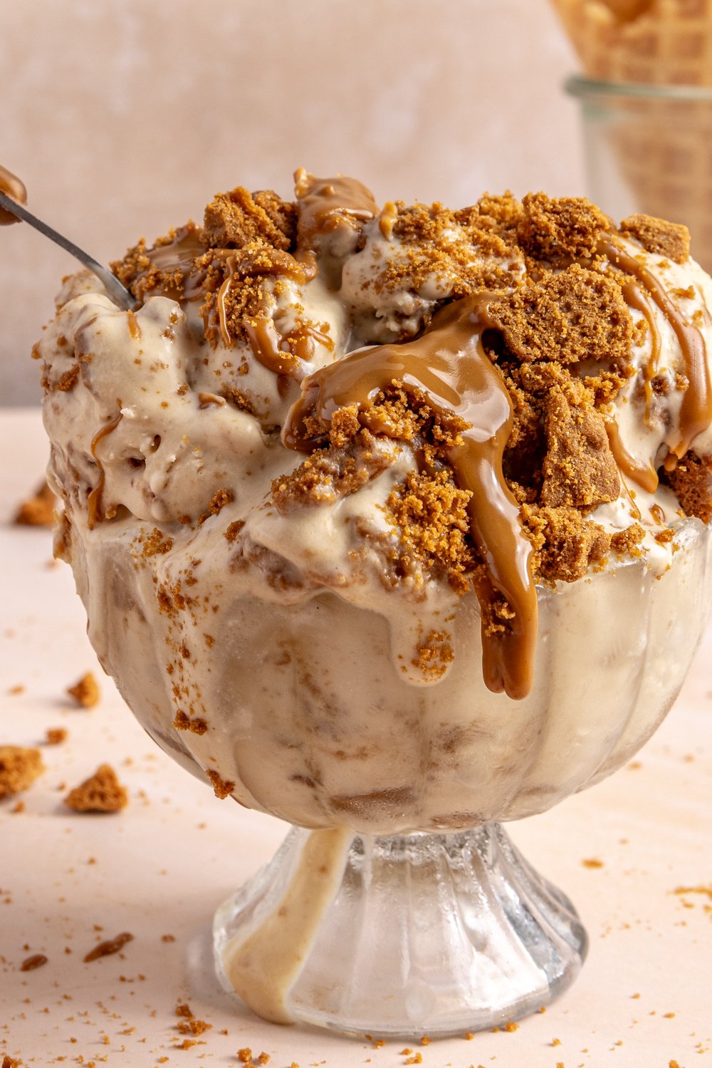 bowl of cookie butter ice cream drizzled with more cookie butter and topped with crumbled biscoff