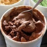 a white tub of homemade chocolate ice cream with a spoon in it.