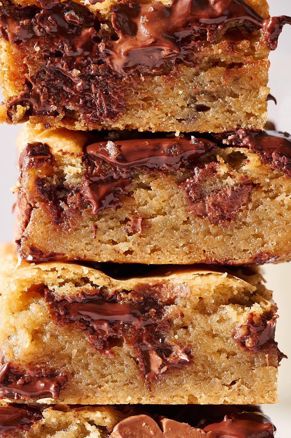close up of stack of browned butter blondies with three kinds of melty chocolate glistening