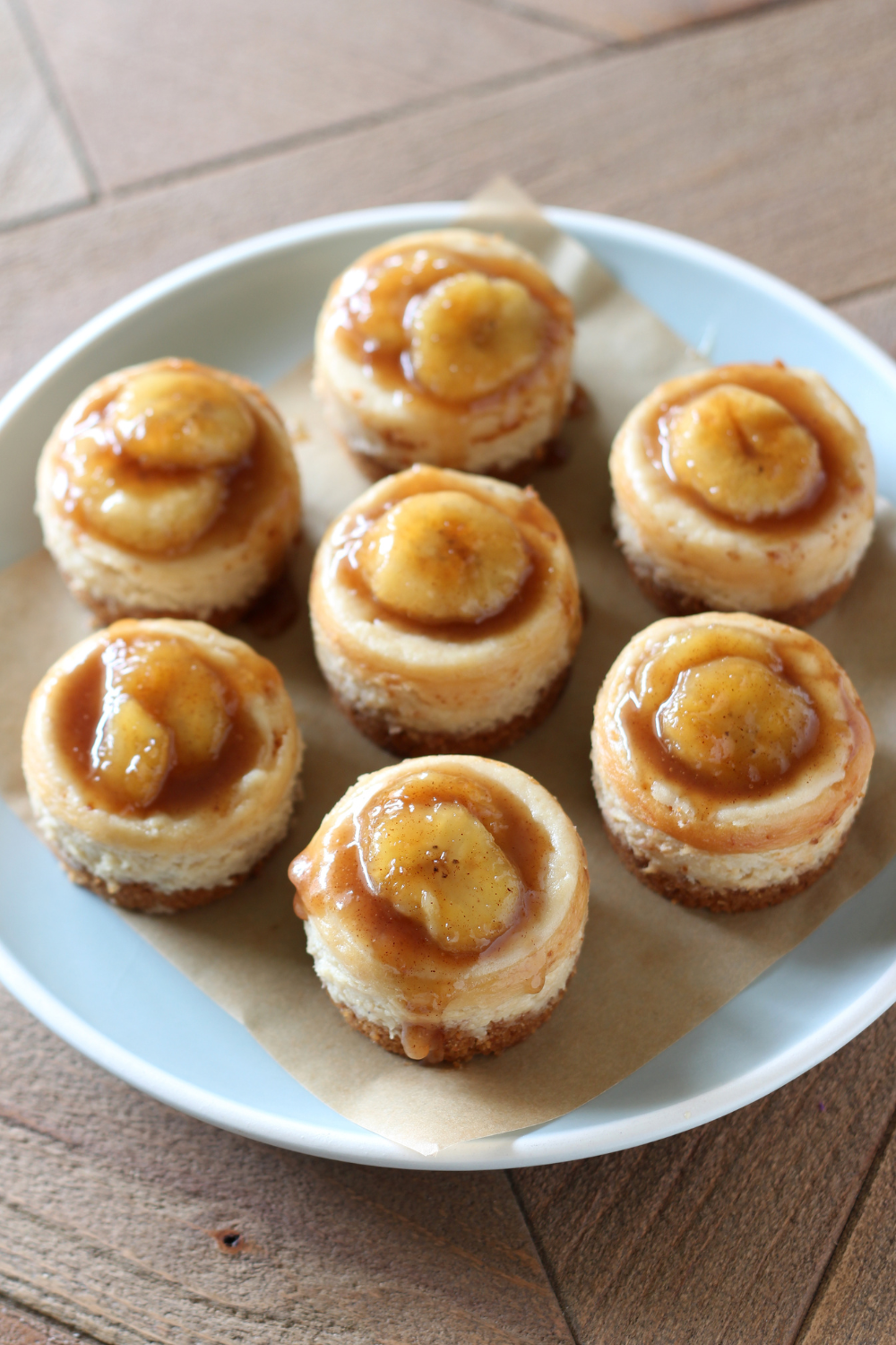 several mini bananas foster cheesecakes, topped with bourbon caramel and banana slices, on a platter, ready to serve