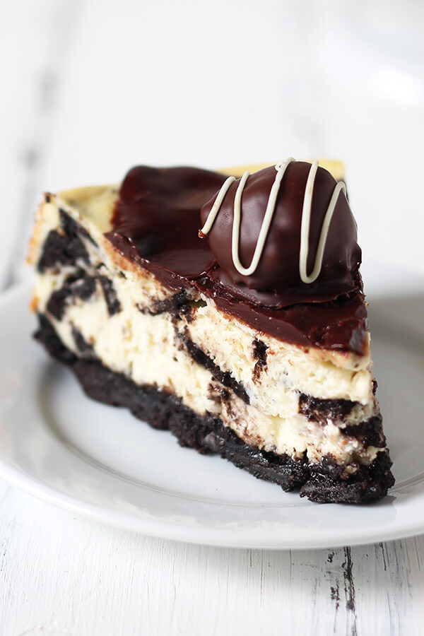 Oreo Cheesecake is a completely over-the-top sinful dessert with an Oreo crust, Oreo cheesecake filling, chocolate ganache, and Oreo truffles on top! Holy YUM.