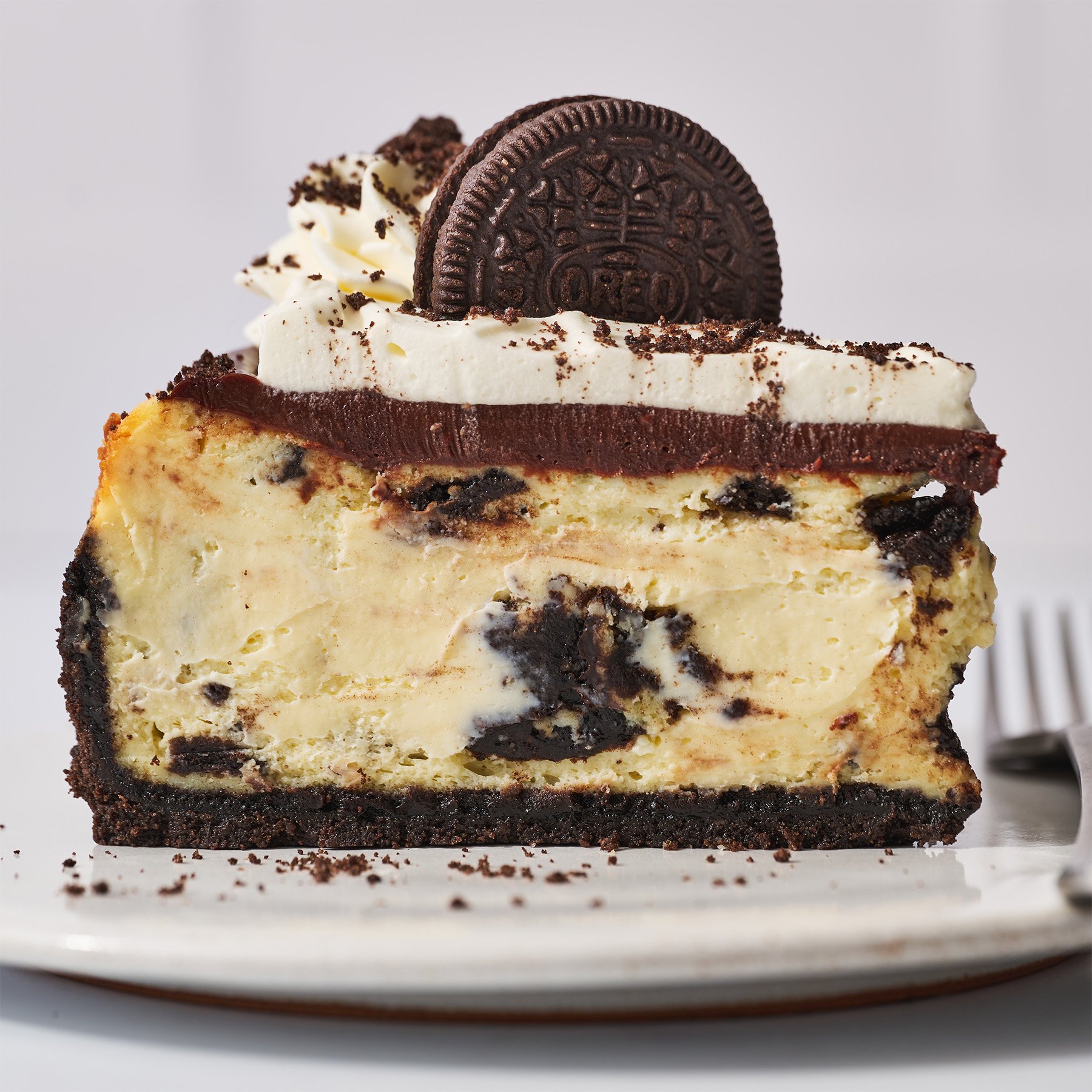 slice of oreo cheesecake with fresh whipped cream and an oreo garnish on top