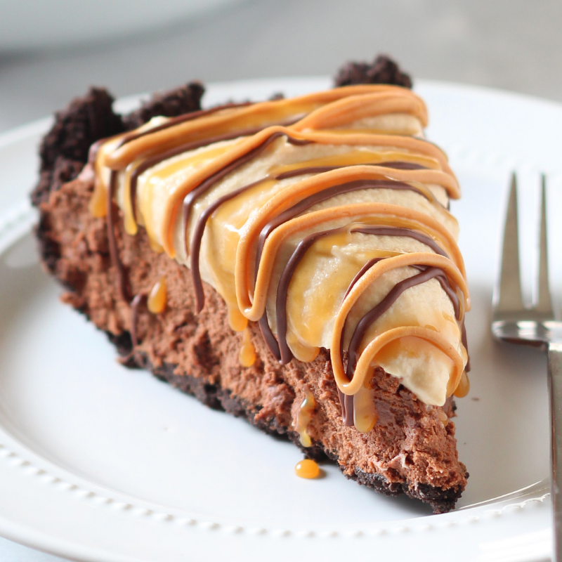 a slice of Chocolate Peanut Butter Caramel Mousse Pie on a plate, with a fork, ready to serve
