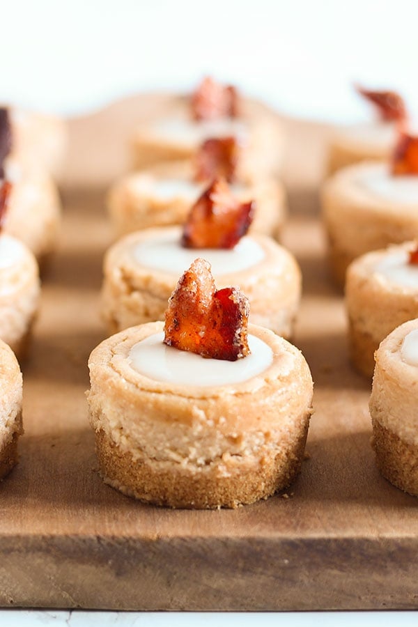 Maple Bacon Mini Cheesecakes are sweet-salty cream cheese perfection! They even have a piece of candied bacon as a garnish AND bacon fat in the graham cracker crust. Talk about YUM.