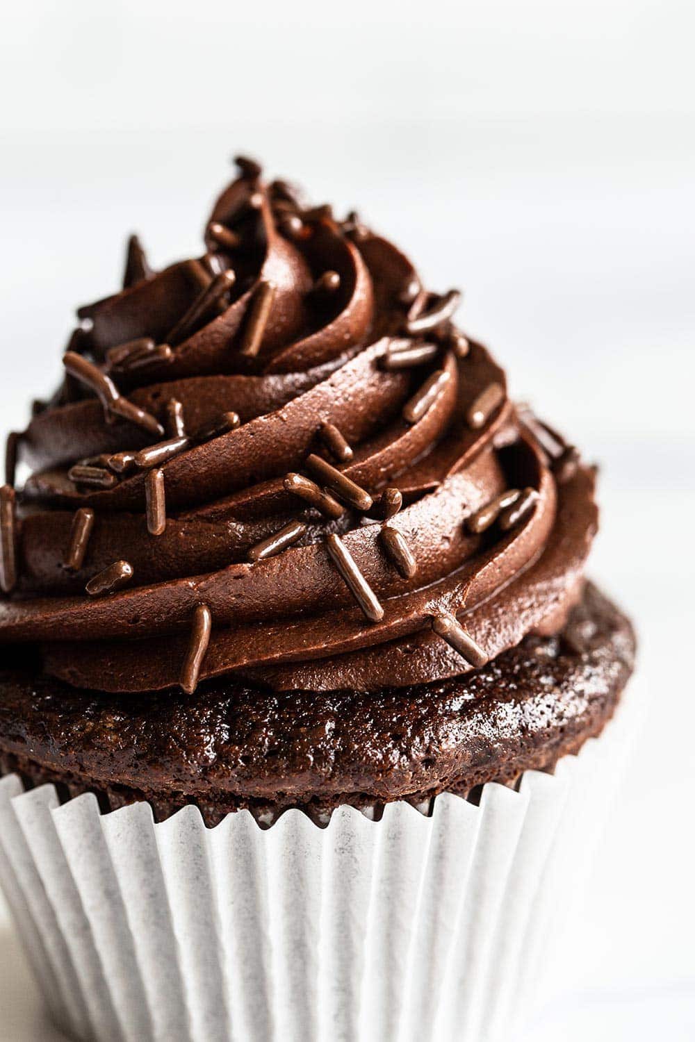 close up of chocolate frosting and chocolate sprinkles on a chocolate cupcake