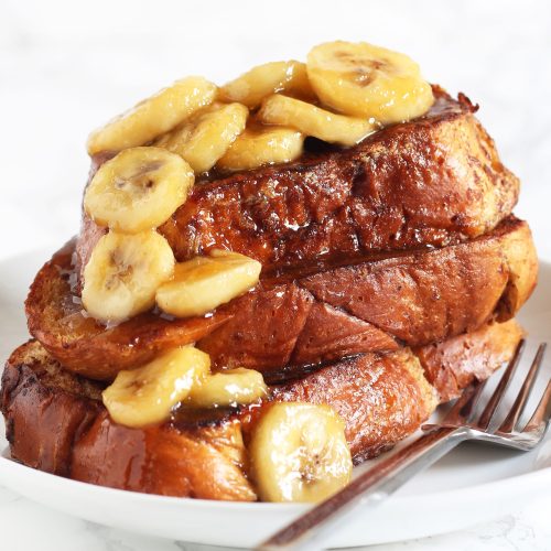 stack of bananas foster French toast on a plate with a fork, ready to serve