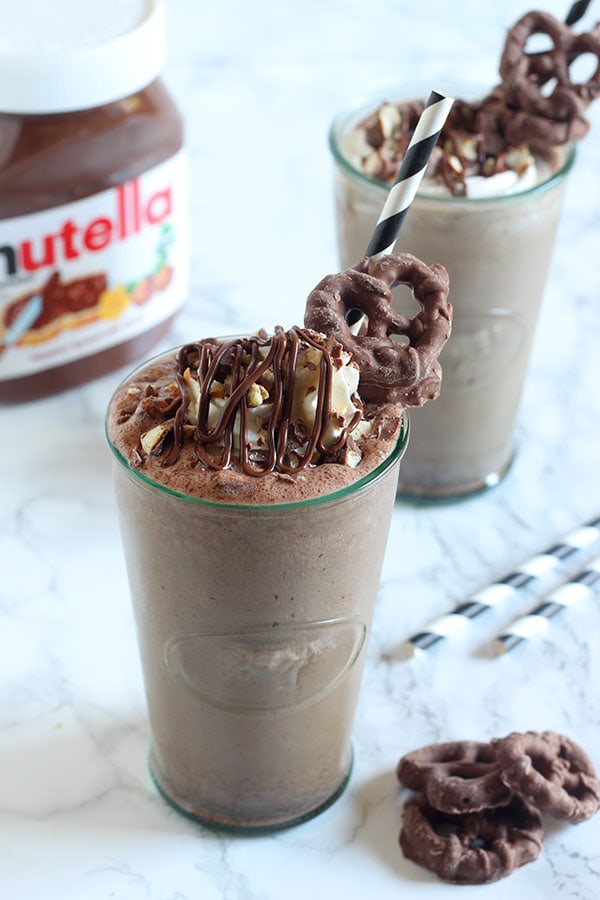 Nutella Chocolate Covered Pretzel Milkshake features a chocolate Nutella milkshake with bits of chocolate covered pretzels, topped with whipped cream, more Nutella, and more pretzels! Complete decadence in a drink.