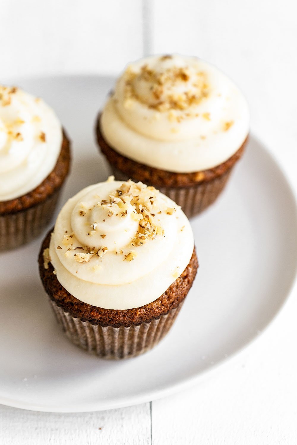 Carrot cupcakes on a plate garnished with chopped walnuts, ready for Easter dessert.