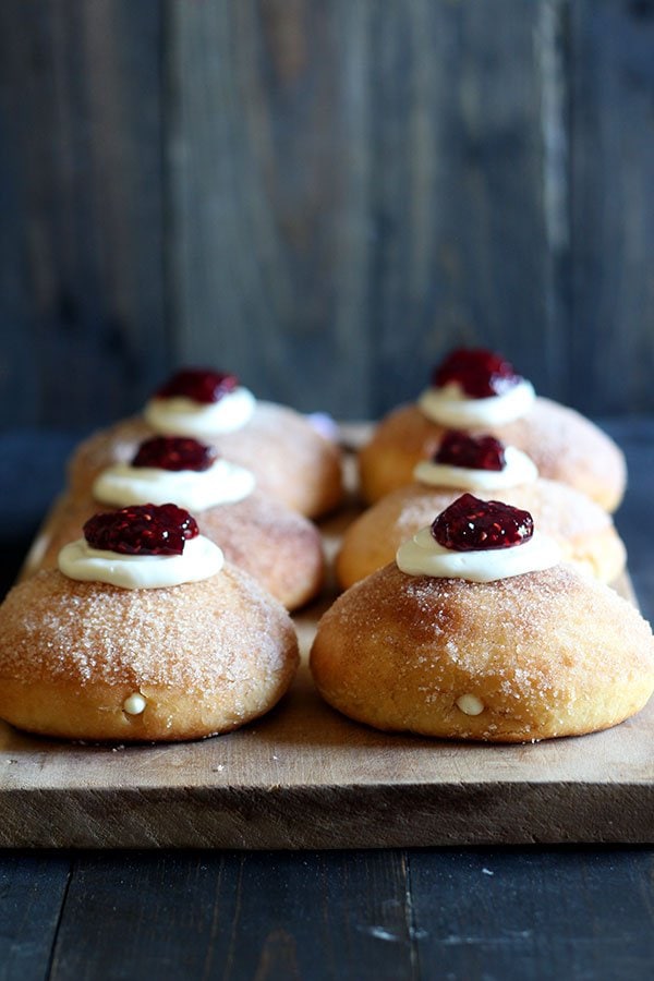 Cheesecake Stuffed Baked Doughnuts feature a fluffy yeast-raised baked doughnut coated in cinnamon sugar, stuffed with sweetened cream cheese, and topped with a dollop of raspberry jam.