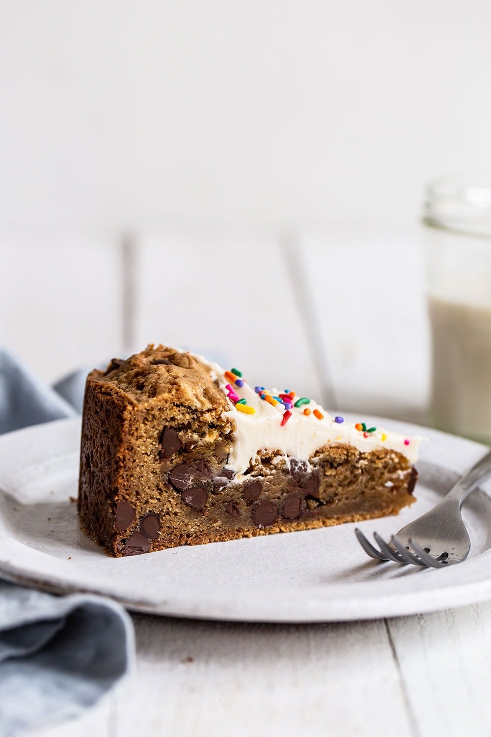Slice of chewy and gooey cookie cake with vanilla frosting on top