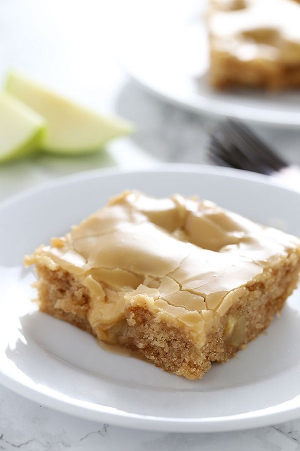 Salted Caramel Apple Sheet Cake slice on a plate with apple wedges in the background