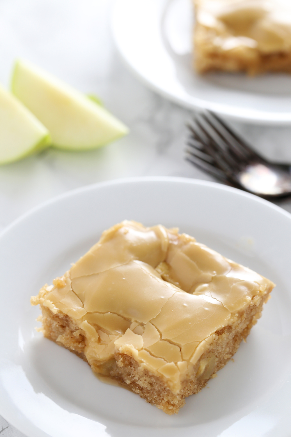 a slice of Salted Caramel Apple Sheet Cake on a plate with a fork, ready to serve
