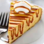a slice of pumpkin cheesecake with salted caramel sauce and whipped cream, on a plate with a fork