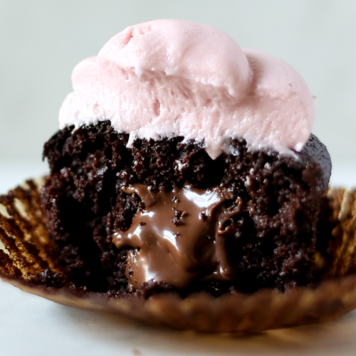 a chocolate cupcake stuffed with Nutella and iced with raspberry buttercream, cut in half to show the filling inside.