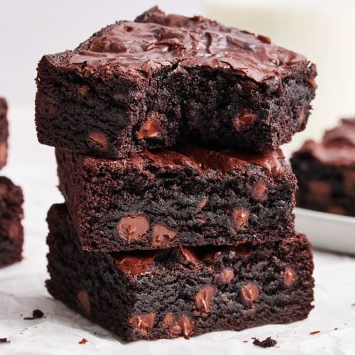 a stack of three brownies, with the top brownie with a bite taken out of it.